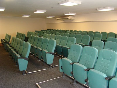 slim auditorium chairs with arms fully upholstered in green fabric in tyr by fleifel furniture